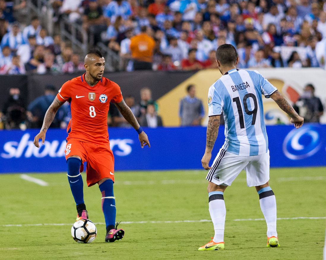 Chile's Arturo Vidal (8) looks to pass the ball while Argentina's Ever Banega defends.